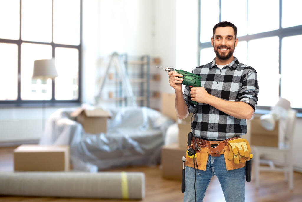 happy male builder with drill and tools at home - Photo, Image
