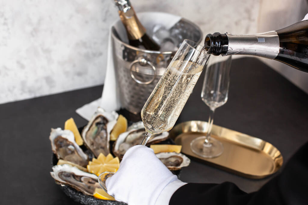 Ręka kelnera z białą rękawiczką nalewająca szampana - Zdjęcie, obraz