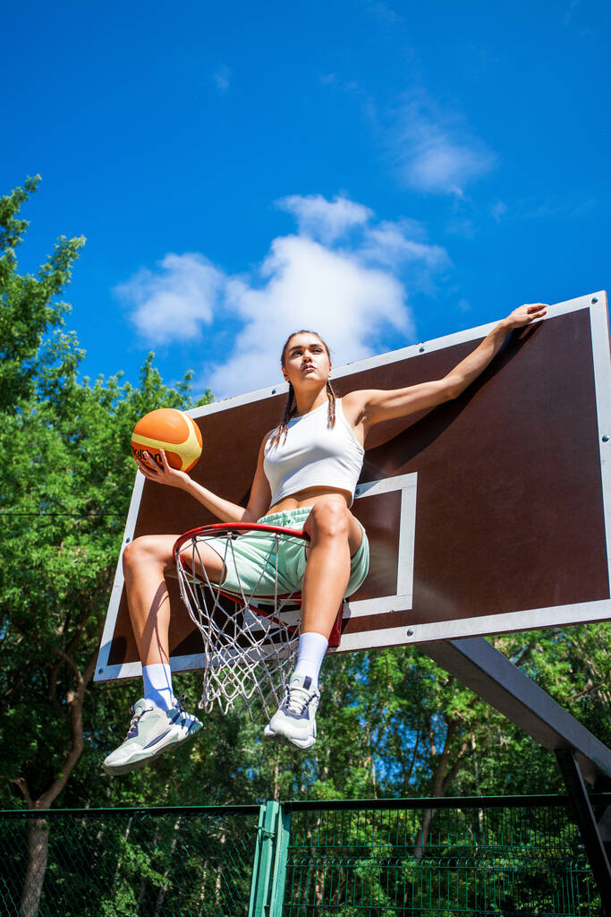 Giovane bella ragazza bruna in posa sul campo da basket - Foto, immagini