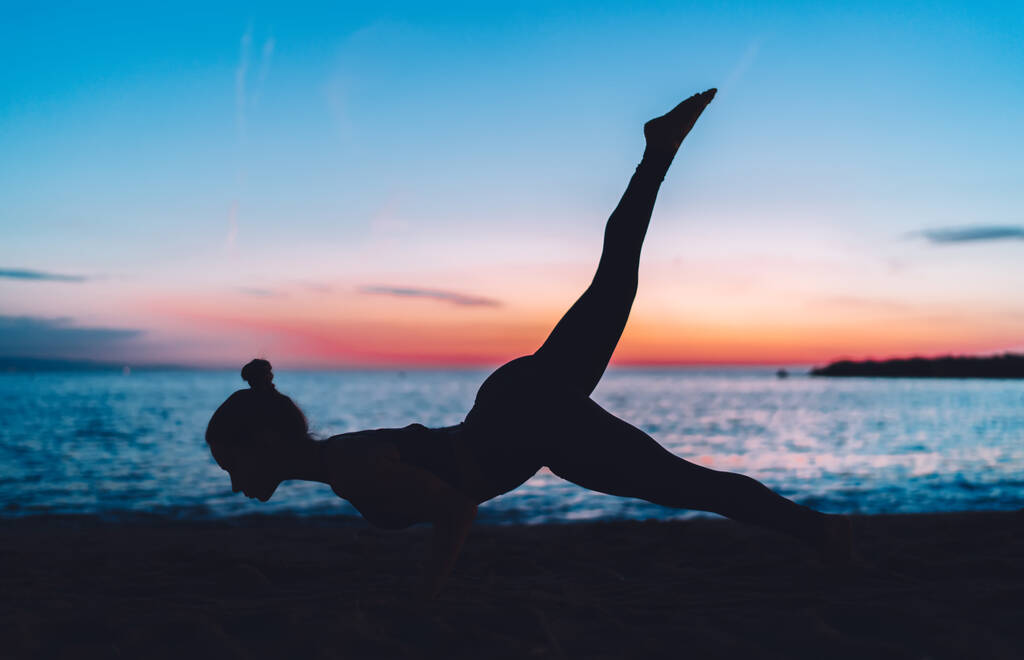 Mujer motivada en la práctica del traje de atletismo estirando la postura del yoga respirando y disfrutando de la recreación en la costa de Oceanía, entrenadora femenina sintiendo inspiración y equilibrio en asana manteniendo la forma del cuerpo - Foto, Imagen