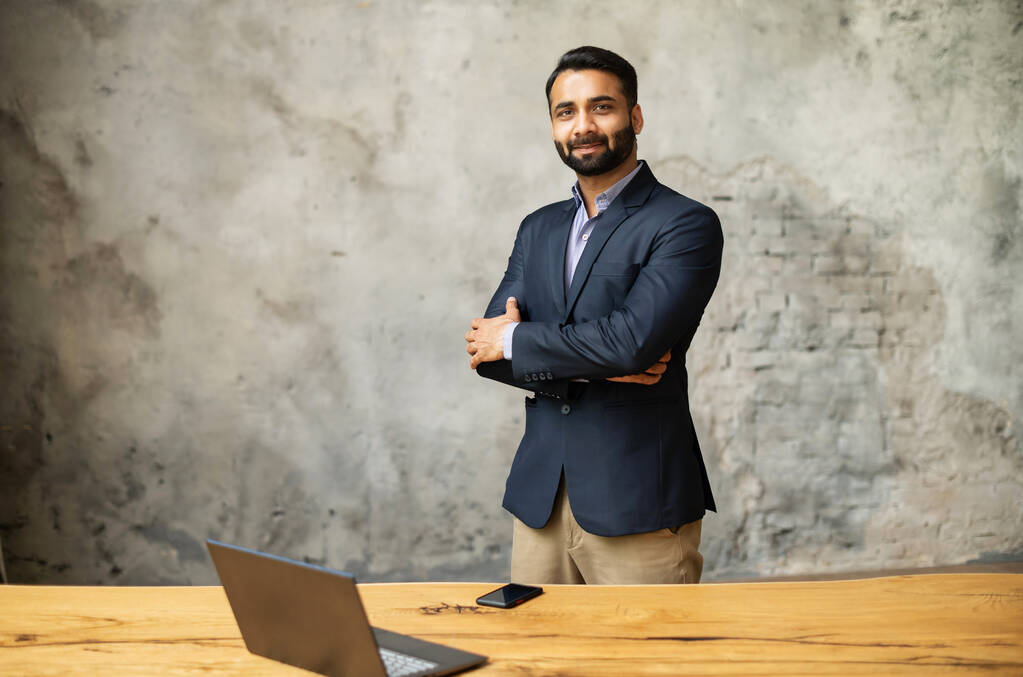 Intialainen liikemies virallisessa puvussa seisoo modernissa toimistossa lähellä pöytää - Valokuva, kuva