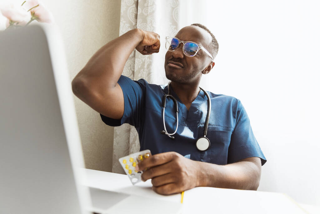 Ein junger afrikanischer Arzt, Therapeut oder medizinischer Berater mit Laptop, Beratung online. Gesundheits-, Pflege-, Medizin- und Berufsbegriff - Foto, Bild