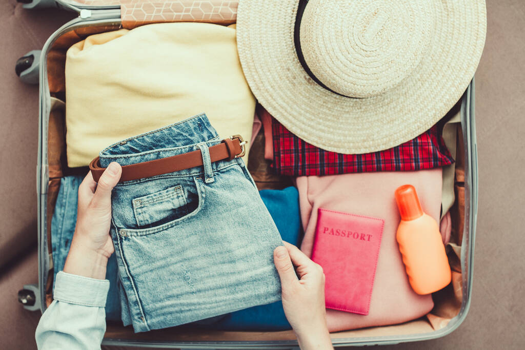 Femme voyageur emballant des vêtements dans une valise pour un nouveau voyage. Bagages pour les vacances et les vacances de voyage. Vue du dessus  - Photo, image