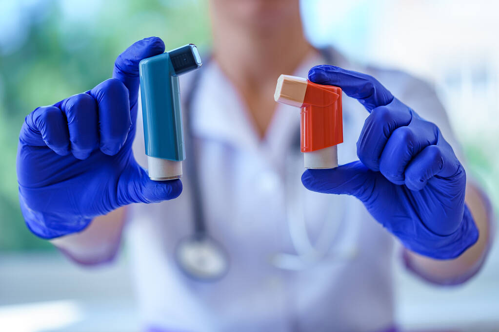 Arts in blauw rubber medische handschoenen houdt astma inhalatoren voor astmapatiënten tijdens medisch overleg en onderzoek. Gezondheidszorg en astma behandeling  - Foto, afbeelding