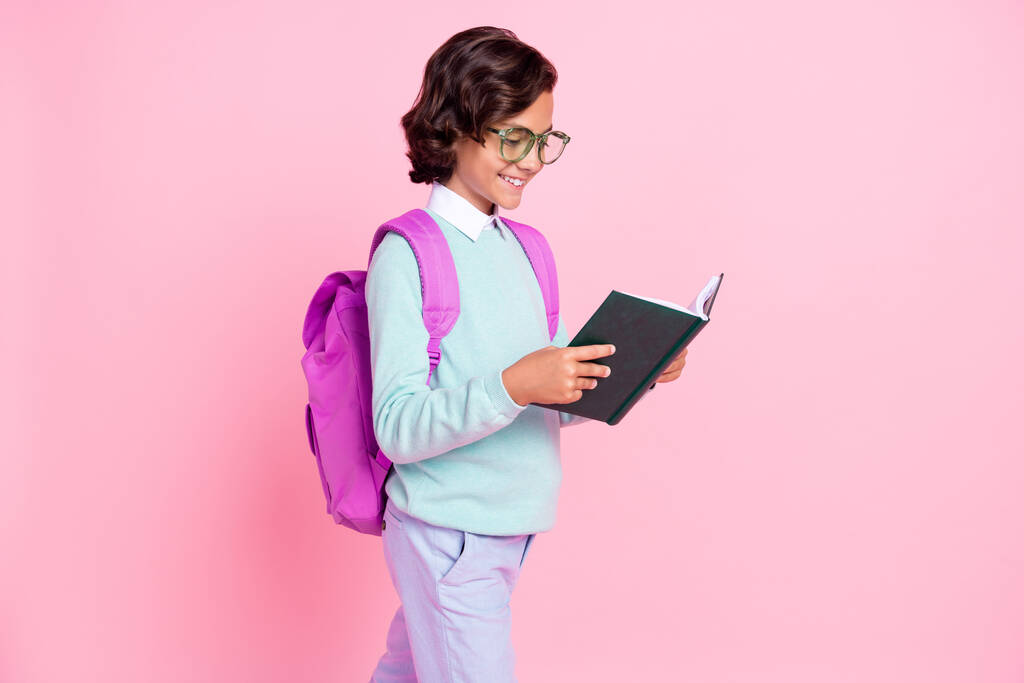 Profiili kuva iloinen poika pidä kirja lukea kävellä kulumista silmälasit laukku sinivihreä paita eristetty vaaleanpunainen väri tausta - Valokuva, kuva