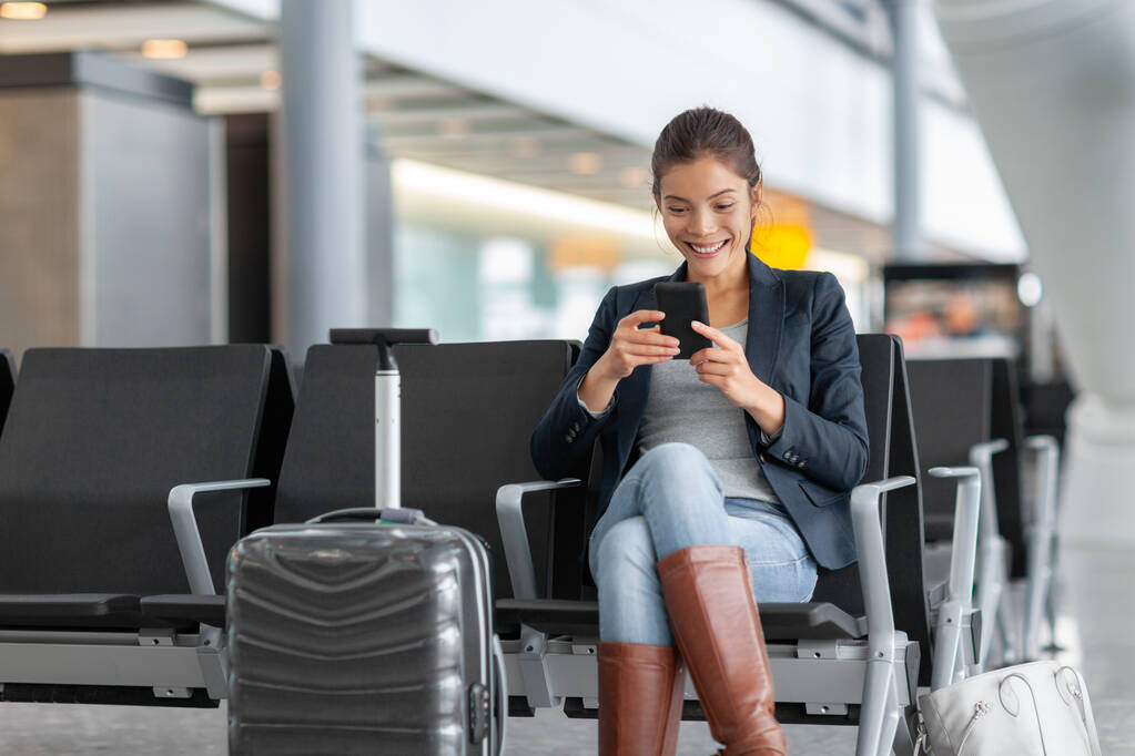 Utazási repülőtér nő használja a mobiltelefon vár a társalgóban a kézipoggyászt. Ázsiai nő üzleti úton okostelefonnal. Technológia wifi szórakoztató online terminál - Fotó, kép