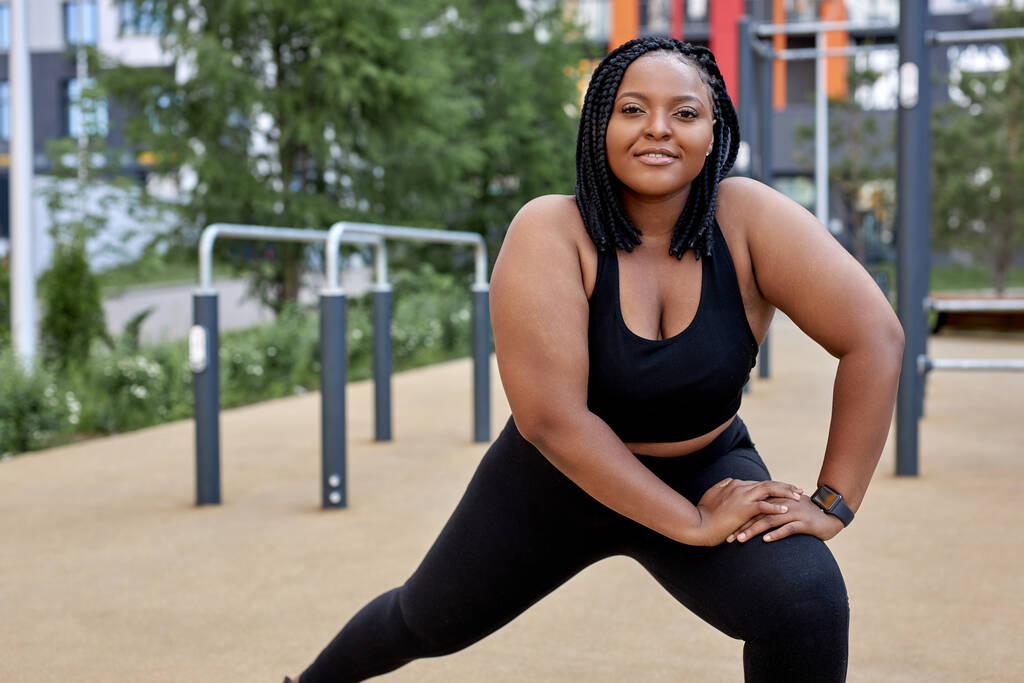adorable fat woman in black tracksuit is engaged in fitness on sports ground, side view portrait - Photo, Image