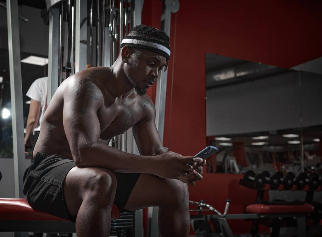 African american athletic guy with phone using sports app for exercising. Gym workout and technologies - Photo, Image