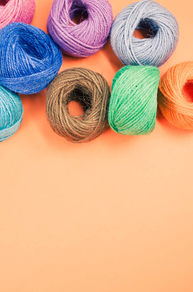 Een close-up shot van zachte kleurrijke textielballen van wol op oranje achtergrond met een kopieerruimte - Foto, afbeelding