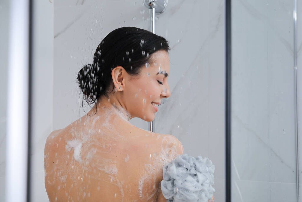 Junge Frau mit Netzhocker unter der Dusche zu Hause - Foto, Bild