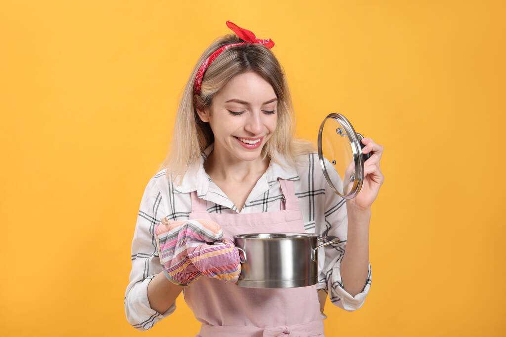 Young housewife with pot on yellow background - Photo, Image