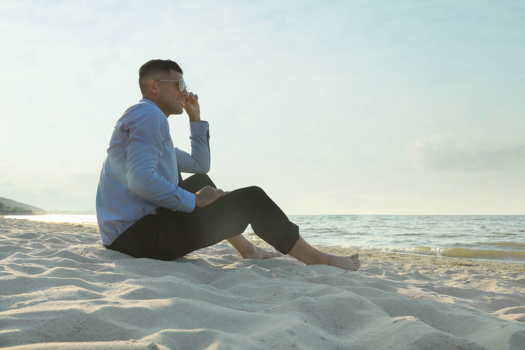 幸せなビジネスマン砂のビーチに座っている。出張 - 写真・画像