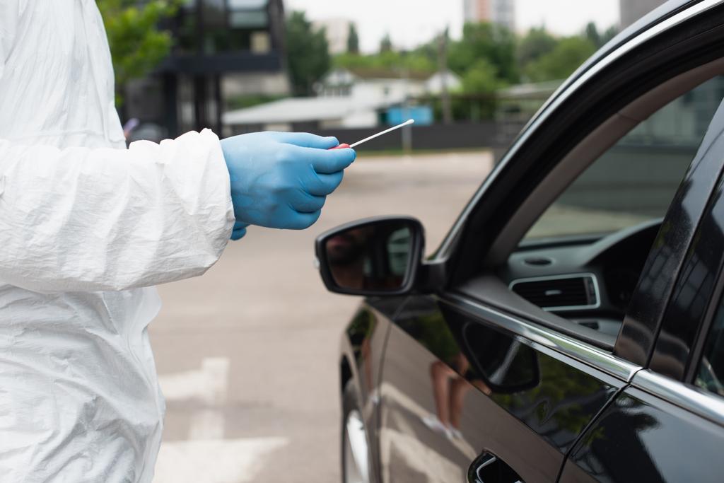 Обрезанный вид медицинского работника, проводящего тест pcr возле автомобиля  - Фото, изображение