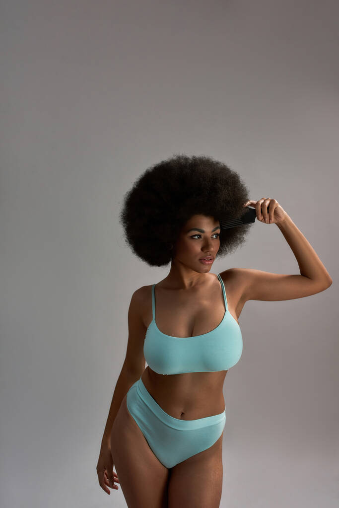 Νεαρή Αφροαμερικανή που ποζάρει κρατώντας χτένα μαλλιών - Φωτογραφία, εικόνα