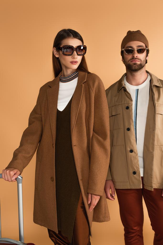 couple of tourists in trendy autumn outfit near suitcase isolated on beige - Fotografie, Obrázek