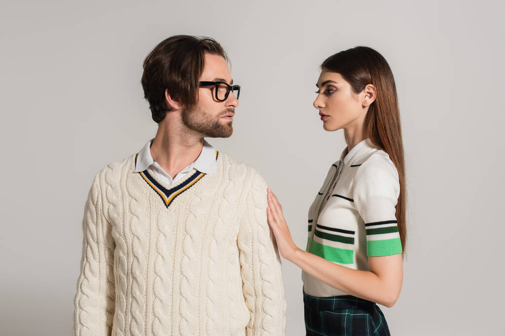 junges Paar in stylischer Kleidung sieht sich vereinzelt auf grau an - Foto, Bild