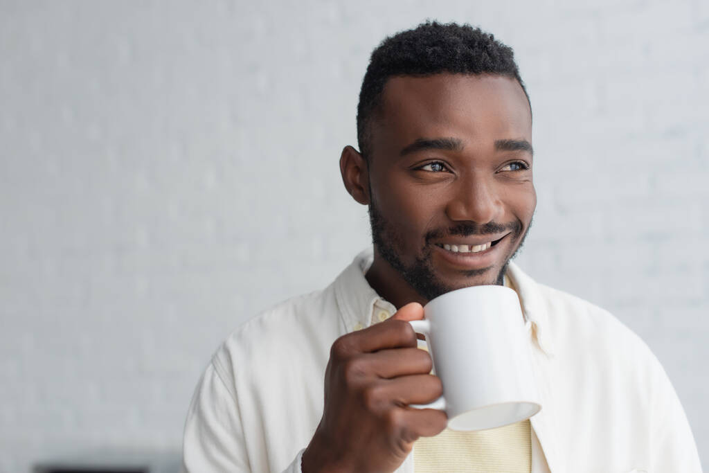 šťastný africký Američan drží šálek kávy v dopoledních hodinách  - Fotografie, Obrázek