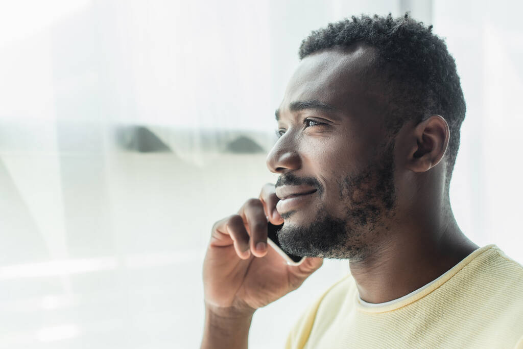 iloinen afrikkalainen amerikkalainen mies puhuu kännykkään kotona - Valokuva, kuva