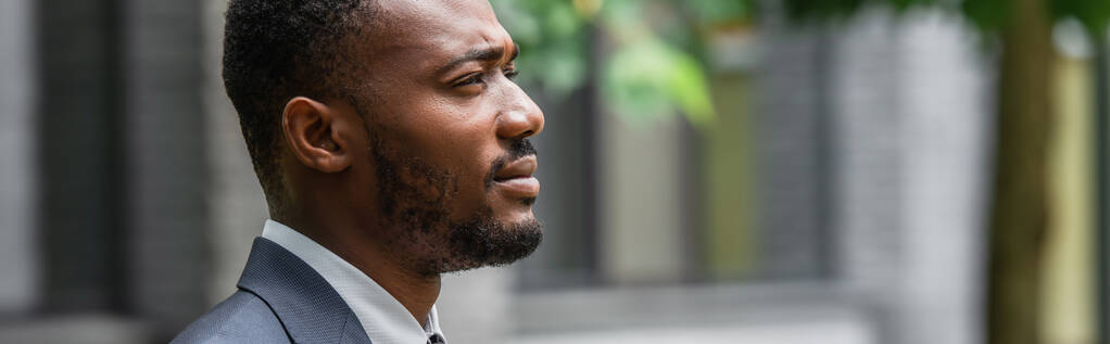 boční pohled na vousatého afroamerického podnikatele v obleku odvracející se pohled, prapor - Fotografie, Obrázek