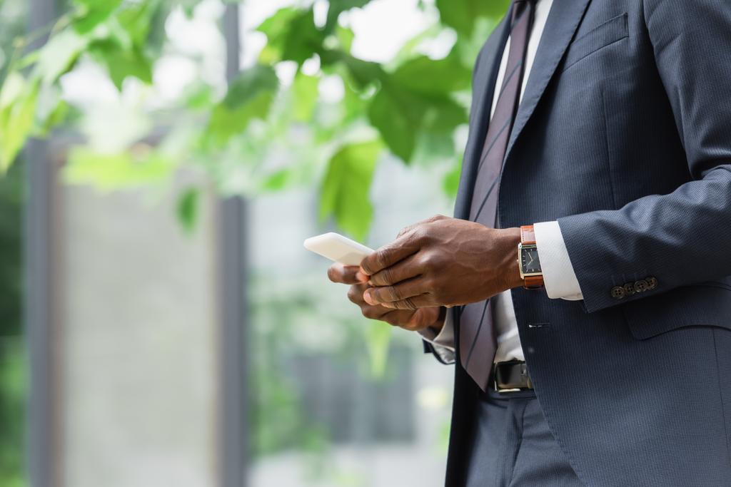 vágott kilátás afro-amerikai üzletember öltönyös üzenetküldés mobiltelefonon  - Fotó, kép