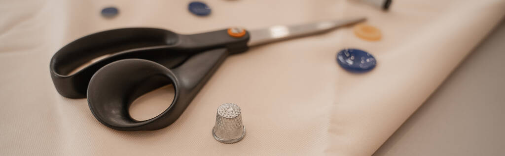 Close up view of sewing scissors and thimble on cloth, banner  - Photo, Image