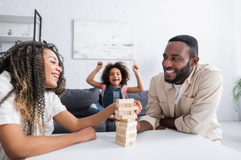 excited african american kid showing win gesture near smiling parents playing wood blocks game - Photo, Image