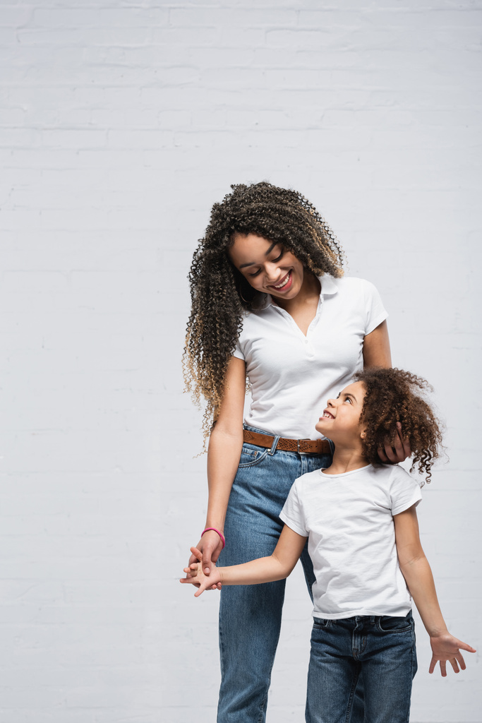 щаслива афроамериканська мама і дочка дивляться один на одного на сірому
 - Фото, зображення