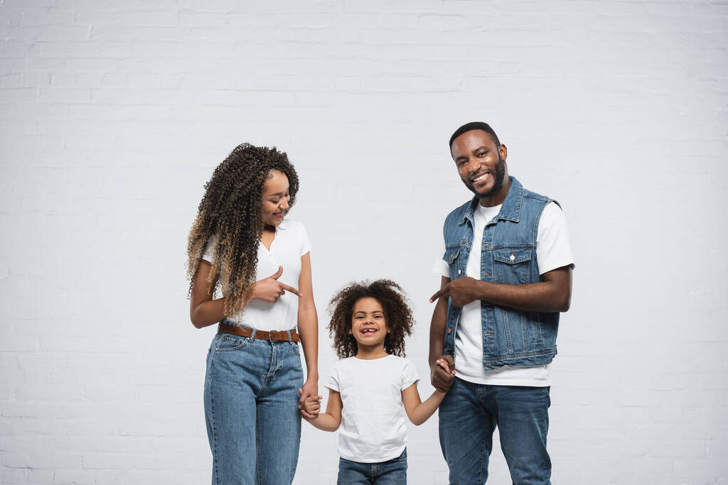 coppia afro-americana indicando figlia su grigio - Foto, immagini