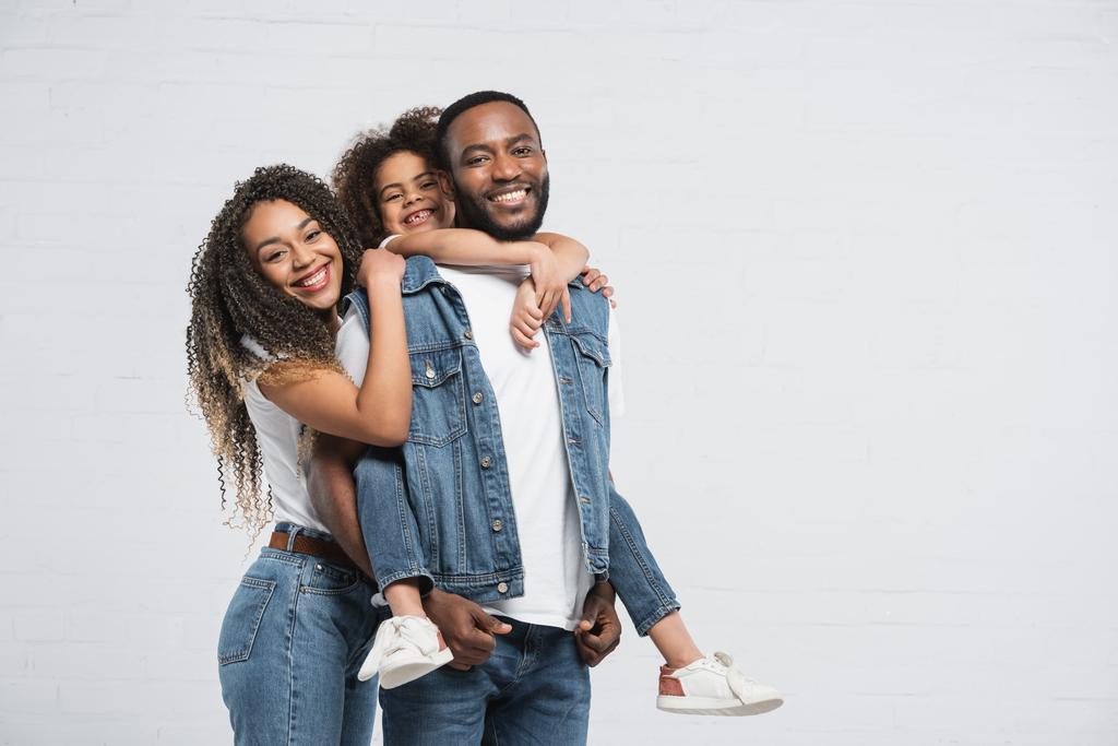 fröhliche afrikanisch-amerikanische Familie blickt in die Kamera auf grau - Foto, Bild
