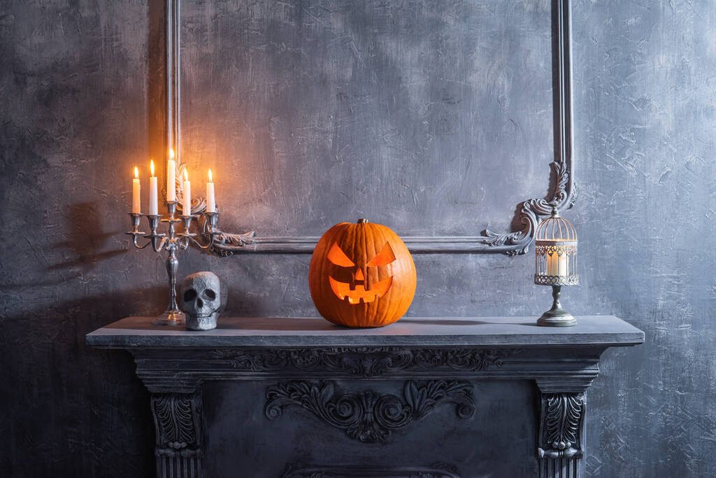 Przerażająca dynia i stara czaszka na starożytnym gotyckim kominku. Halloween, czary i magia. - Zdjęcie, obraz