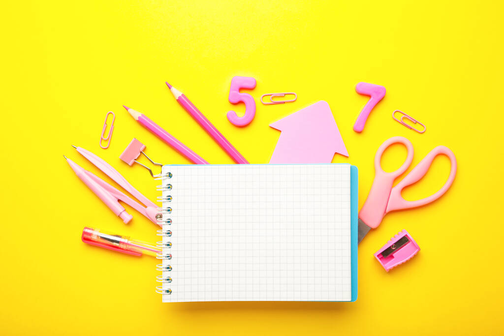 Material escolar rosa con cuaderno sobre fondo amarillo. De vuelta a la escuela. Acostado. Vista superior - Foto, Imagen