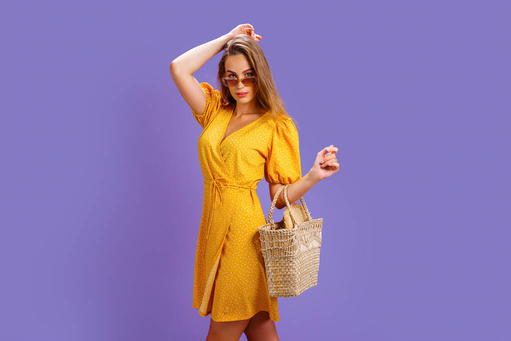 Güzel sarı elbiseli ve saman çantalı şık bir kadın. Moda bahar yaz fotoğrafı. - Fotoğraf, Görsel