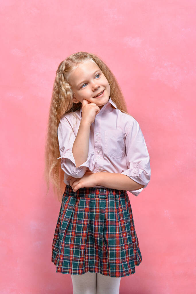 Droomend klein meisje schoolmeisje. roze achtergrond - Foto, afbeelding