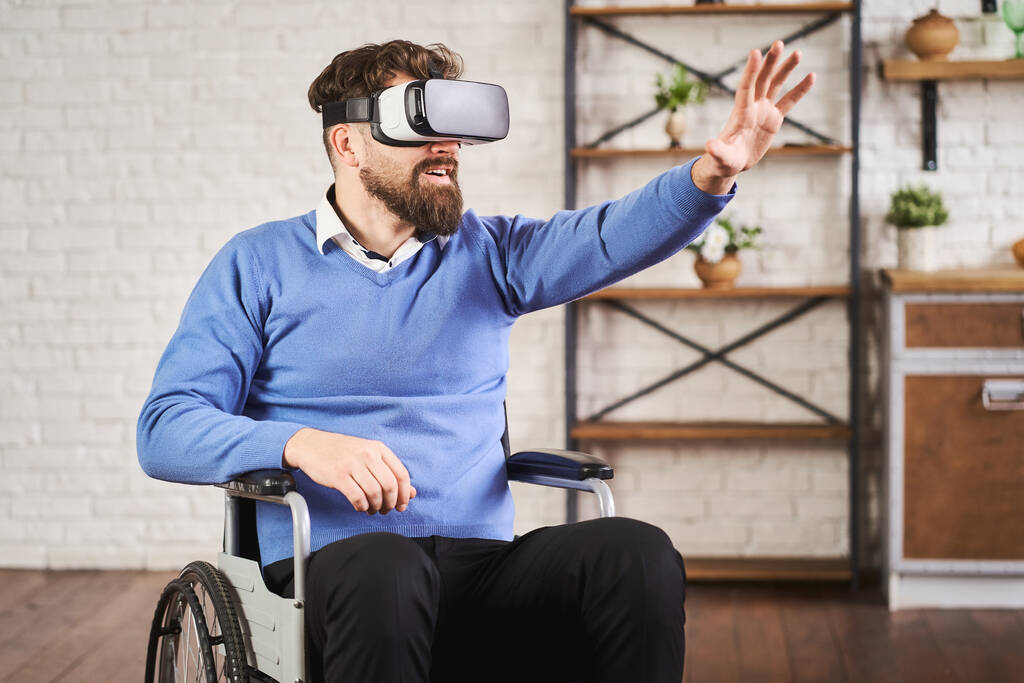 Portret van een man die op een rolstoel zit en een VR-headset gebruikt - Foto, afbeelding