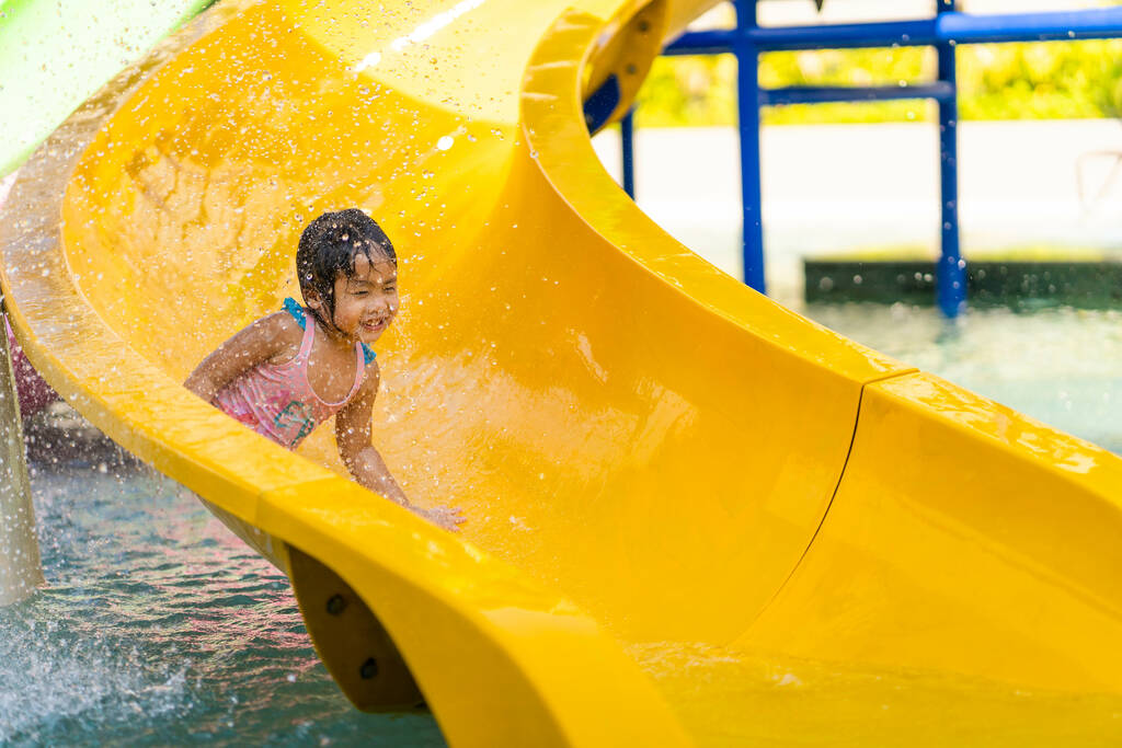 A closeup of a little girl sliding down on a yellow waterslide. - Photo, Image
