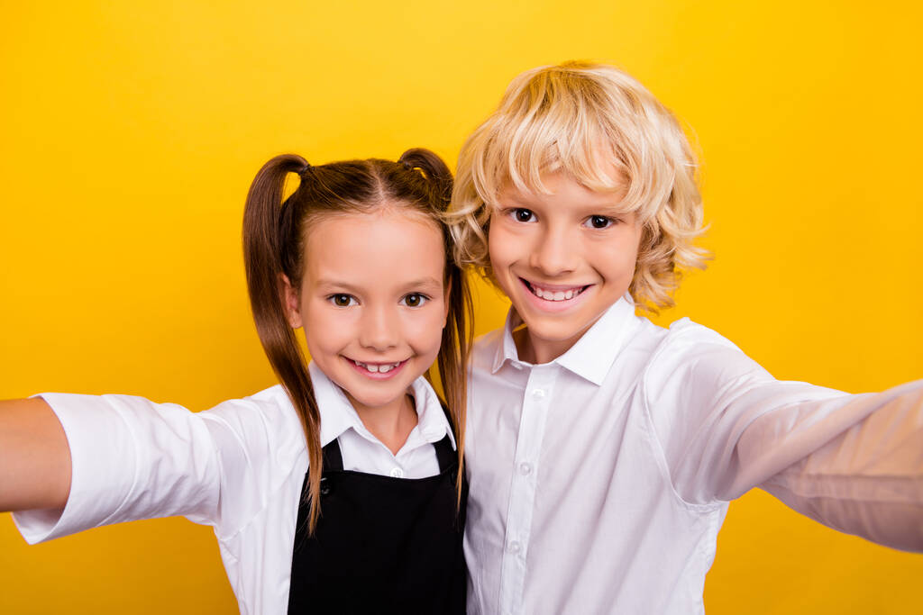 Фото двух положительных школьников снимают селфи зубастые улыбки носить школьную форму изолированный желтый цвет фона - Фото, изображение