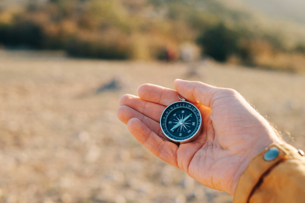 Compass lies in the palm of a tourist in the mountains during sunset. - Foto, Imagem
