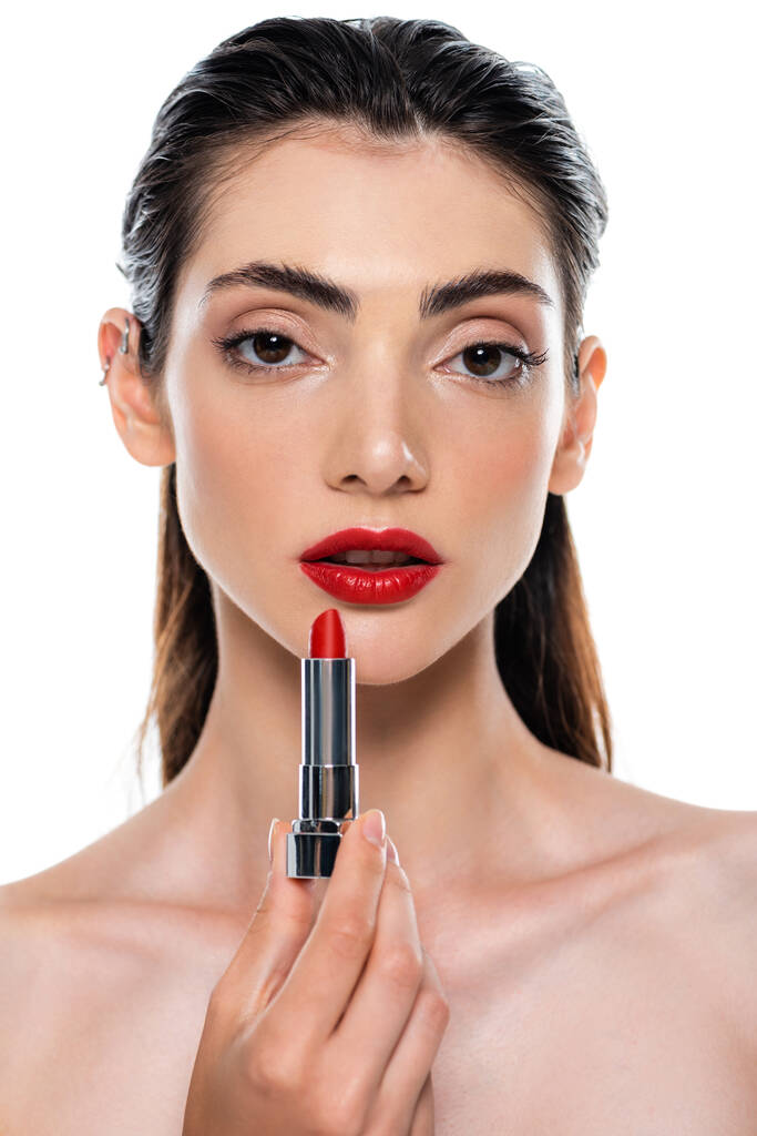 brunette jonge vrouw met rode lippen houden lippenstift geïsoleerd op wit - Foto, afbeelding
