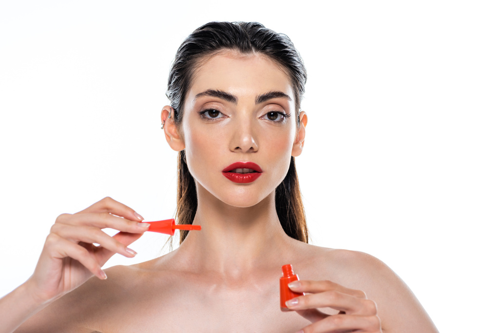 jonge vrouw met rode lippen houden nagellak geïsoleerd op wit  - Foto, afbeelding