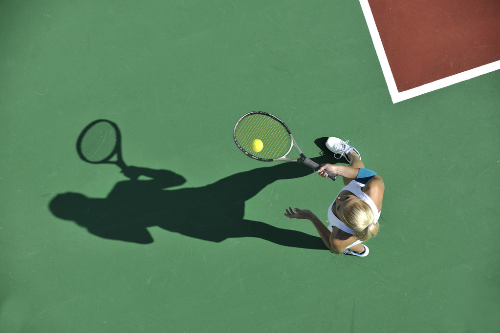 Jovem apto mulher jogar tênis ao ar livre no campo de tênis laranja no início da manhã
 - Foto, Imagem