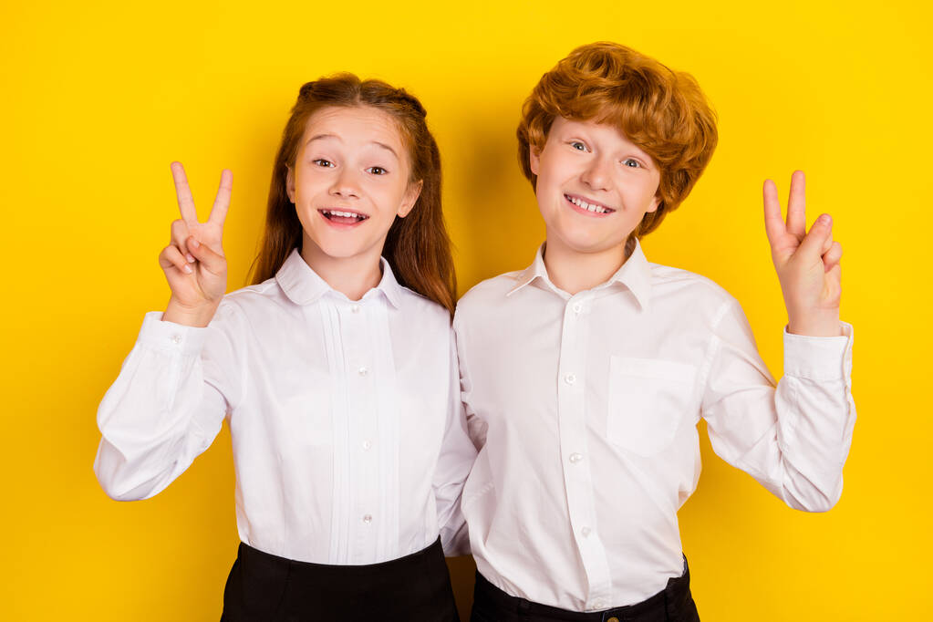 Fénykép a jó hangulat pozitív mosolygós iskolások mutatják v-jel vissza az iskolába elszigetelt sárga színű háttér - Fotó, kép