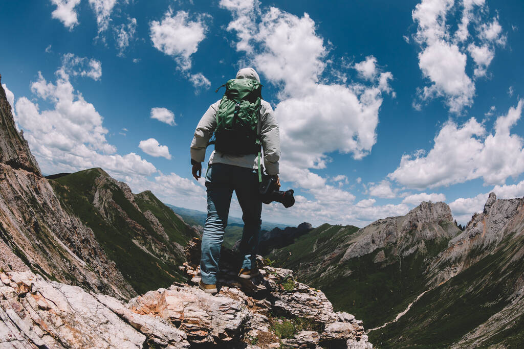 Yükseklerdeki dağın tepesinde kameralı başarılı bir kadın yürüyüşçü. - Fotoğraf, Görsel