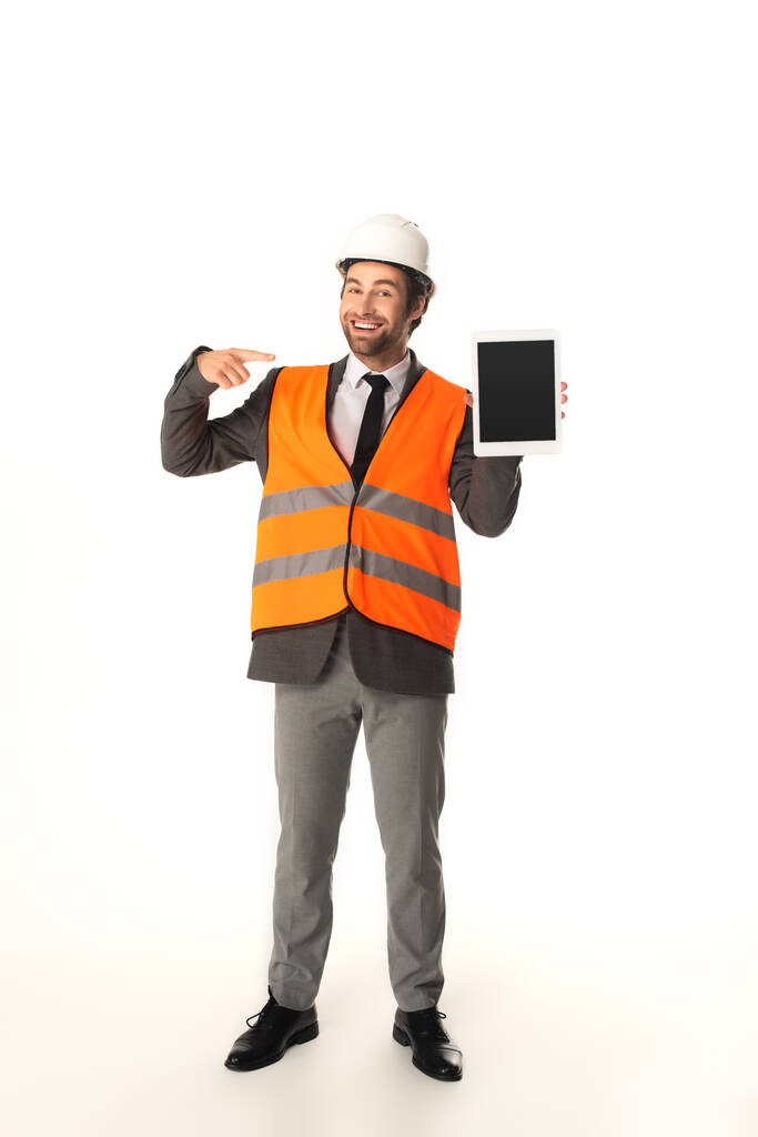 Ingeniero sonriente apuntando a la tableta digital sobre fondo blanco  - Foto, imagen