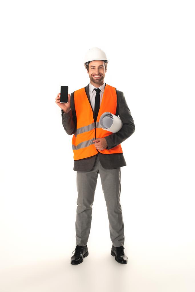 Lächelnder Ingenieur mit Smartphone und Blaupause auf weißem Hintergrund  - Foto, Bild