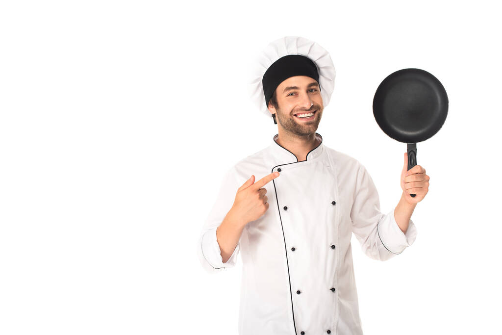 Chef em uniforme apontando para frigideira isolada em branco  - Foto, Imagem