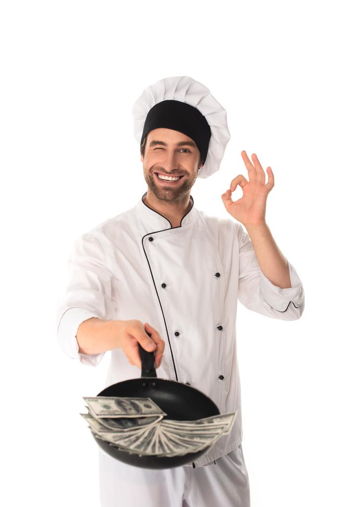 Шеф-кухар показує добре жест і тримає сковороду з доларами ізольовано на білому
  - Фото, зображення