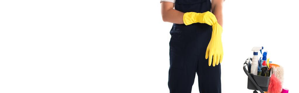 Vista recortada del limpiador con guantes de goma cerca del carro aislado en blanco, pancarta  - Foto, Imagen