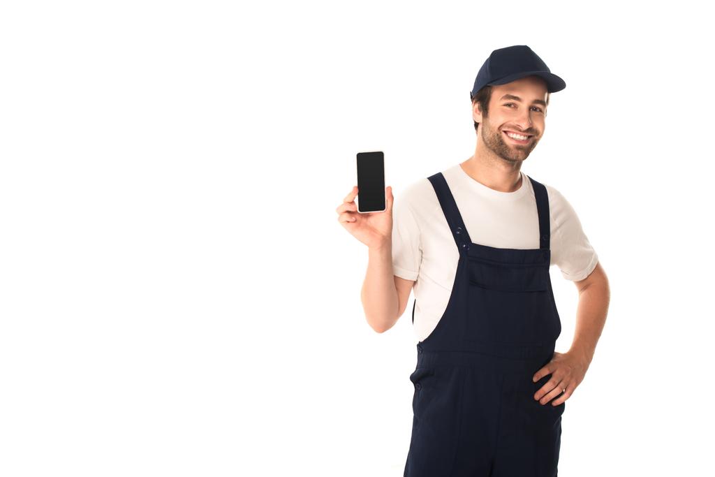 Hymyilevä siivooja tilalla älypuhelin ja käsi lonkan eristetty valkoinen  - Valokuva, kuva