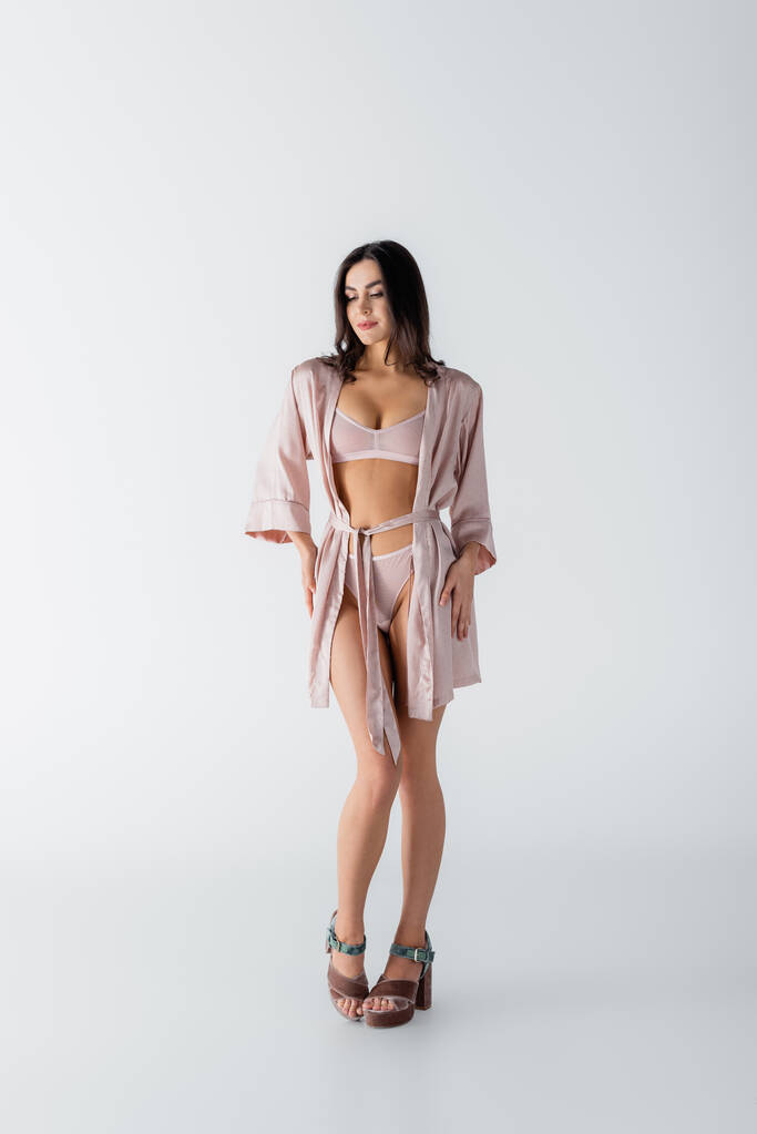full length of young woman posing in underwear and silk robe on white - Photo, Image