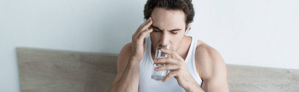 źle człowiek dotyka głowy i wody pitnej podczas gdy cierpi na migrenę, sztandar - Zdjęcie, obraz